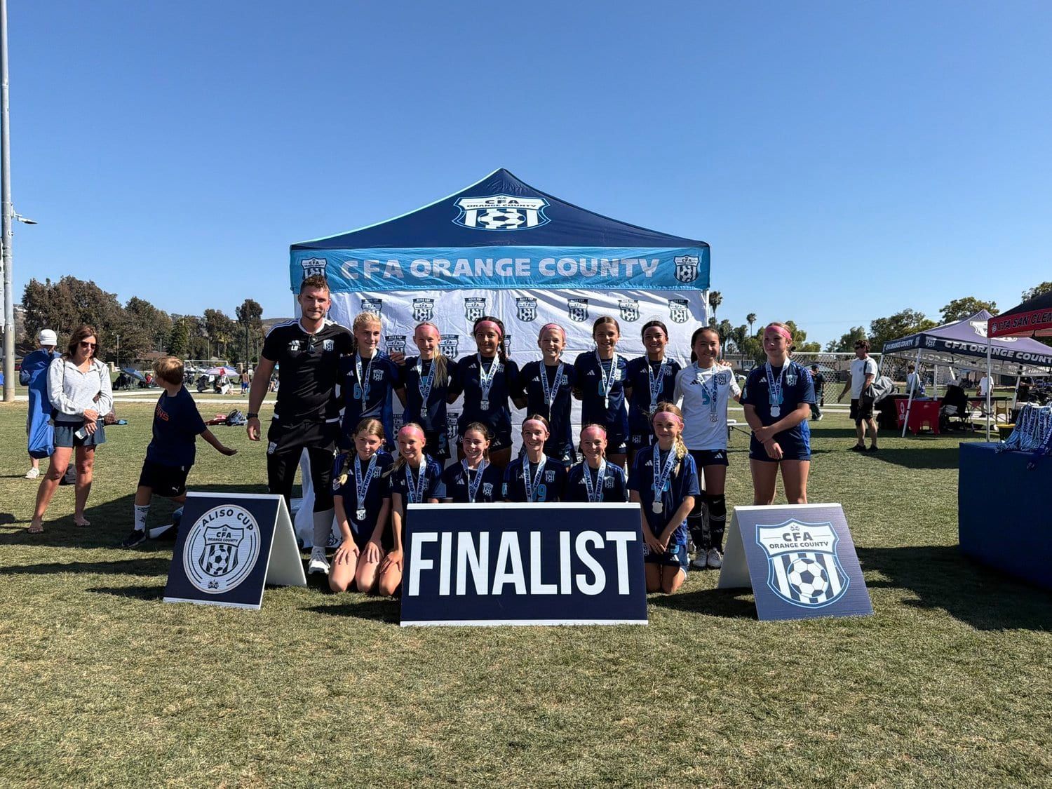 Girls team with their finalist medals at the tournament tent